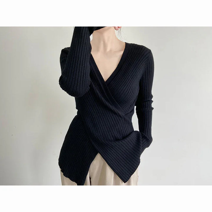 Woman wearing black ribbed wrap sweater with V-neck and beige pants against white background