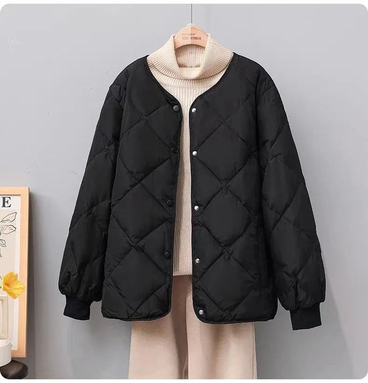 Black quilted button-up jacket over beige turtleneck sweater and pants on wooden hanger