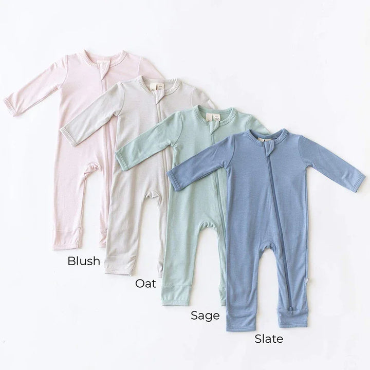 Four baby onesies in blush, oat, sage, and slate colors with front zippers on white background