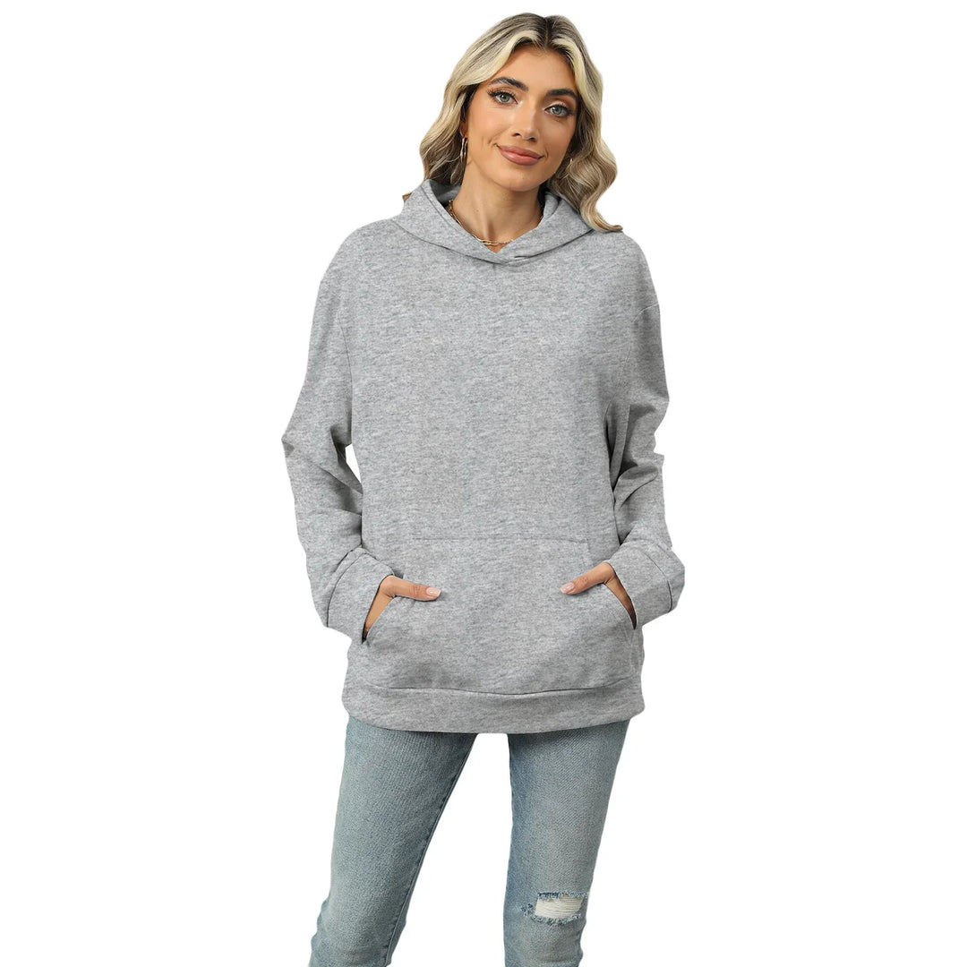 Blonde woman wearing light gray hoodie and ripped blue jeans on white background