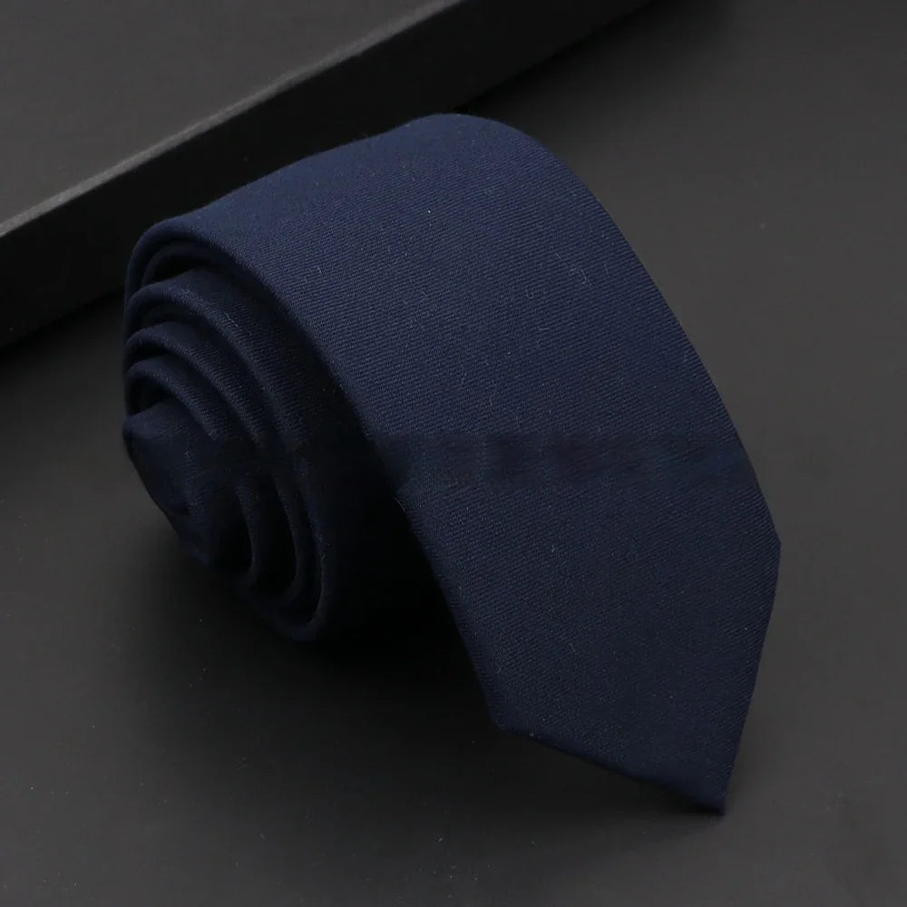 Rolled navy blue men's necktie on black surface with subtle texture