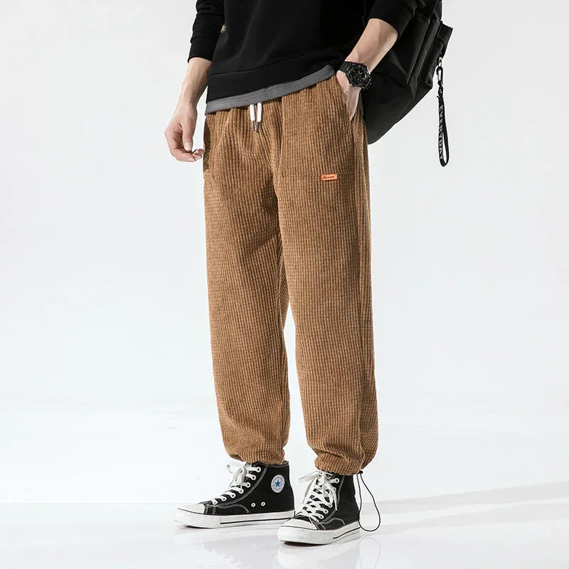 Person wearing brown corduroy jogger pants and black high-top sneakers with white laces