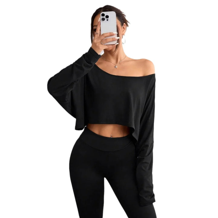 Woman wearing black off-shoulder crop top and high-waisted leggings taking a mirror selfie