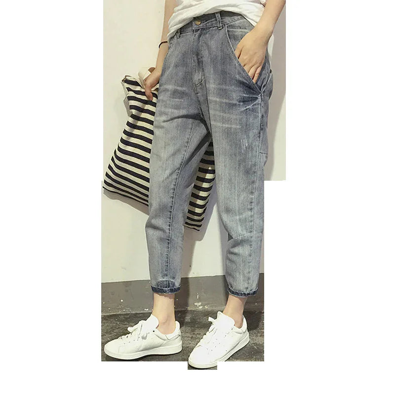 Person wearing relaxed fit light washed denim jeans and white sneakers holding striped pillow