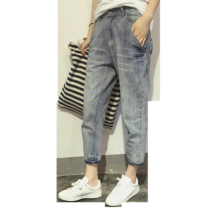 Person wearing relaxed fit light washed denim jeans and white sneakers holding striped pillow