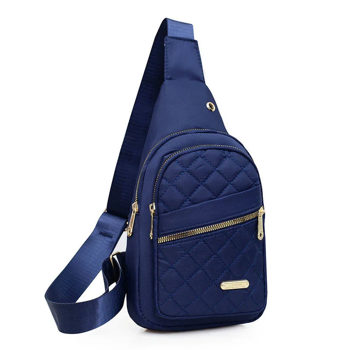 Navy blue quilted crossbody sling bag with gold zippers and adjustable strap