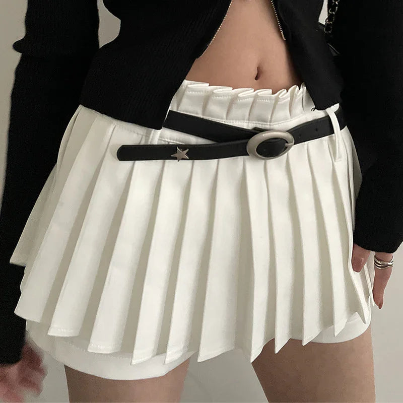 Close-up of white pleated mini skirt with black belt featuring star detail, paired with black cropped top