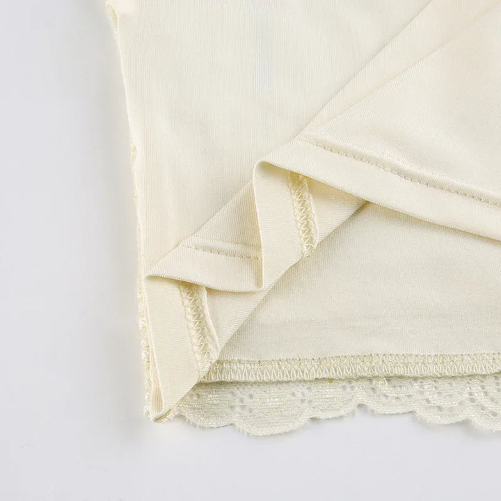 Close-up of beige fabric with lace trim and folded hem detail on white background