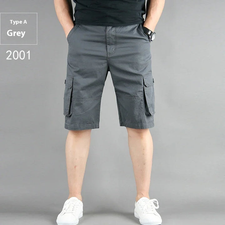Men's grey cargo shorts with pockets, worn with black shirt and white sneakers on grey background