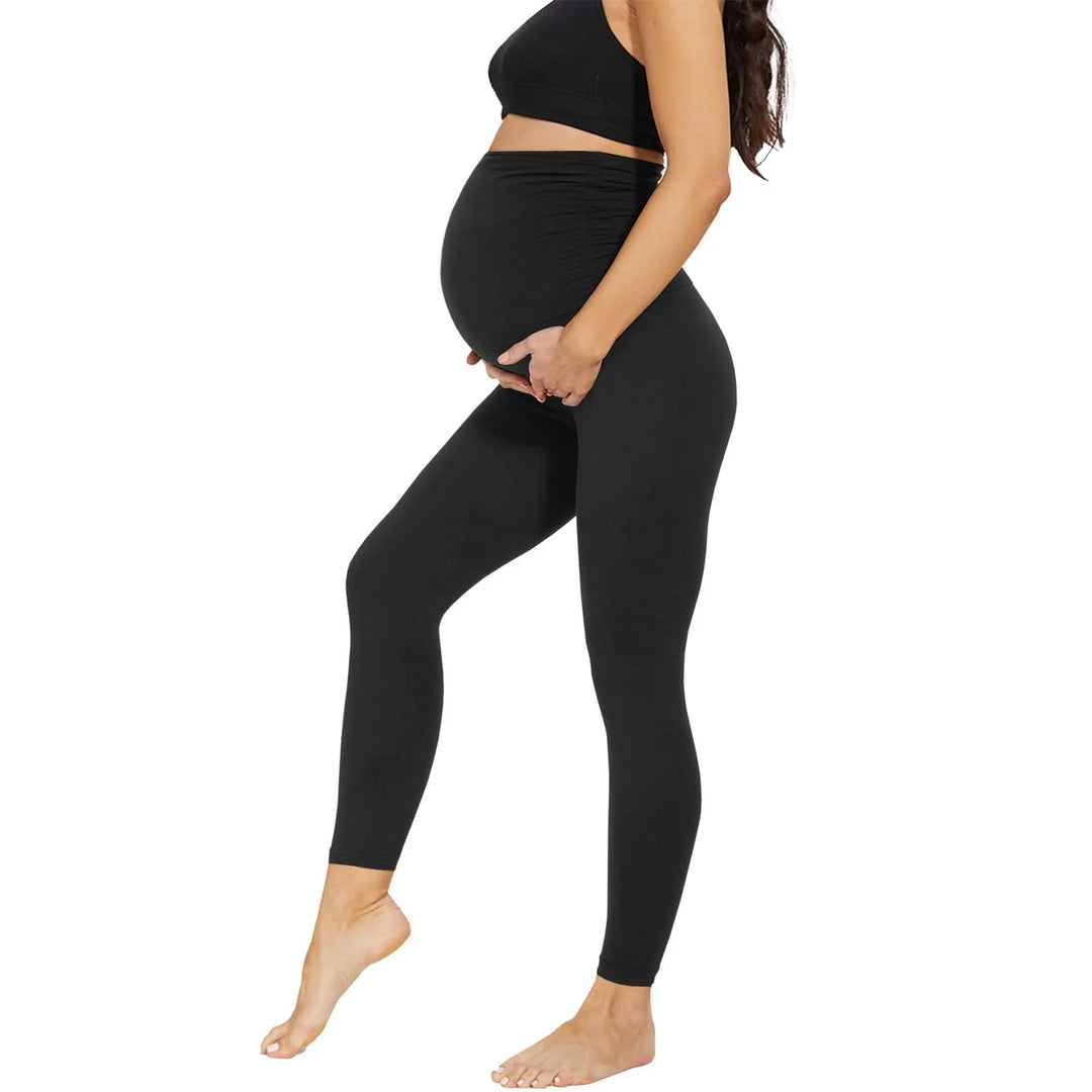Pregnant woman wearing black maternity leggings and crop top on white background