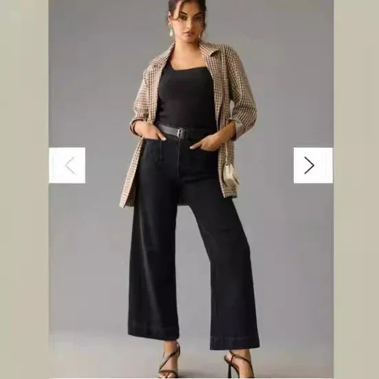 Woman wearing black wide-leg pants, black top, plaid open jacket, and heels in studio