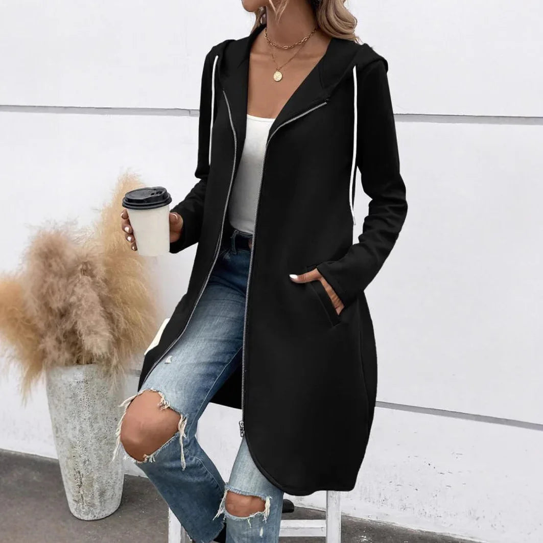 Woman wearing black long zip-up hoodie with white drawstrings and ripped jeans holding coffee cup