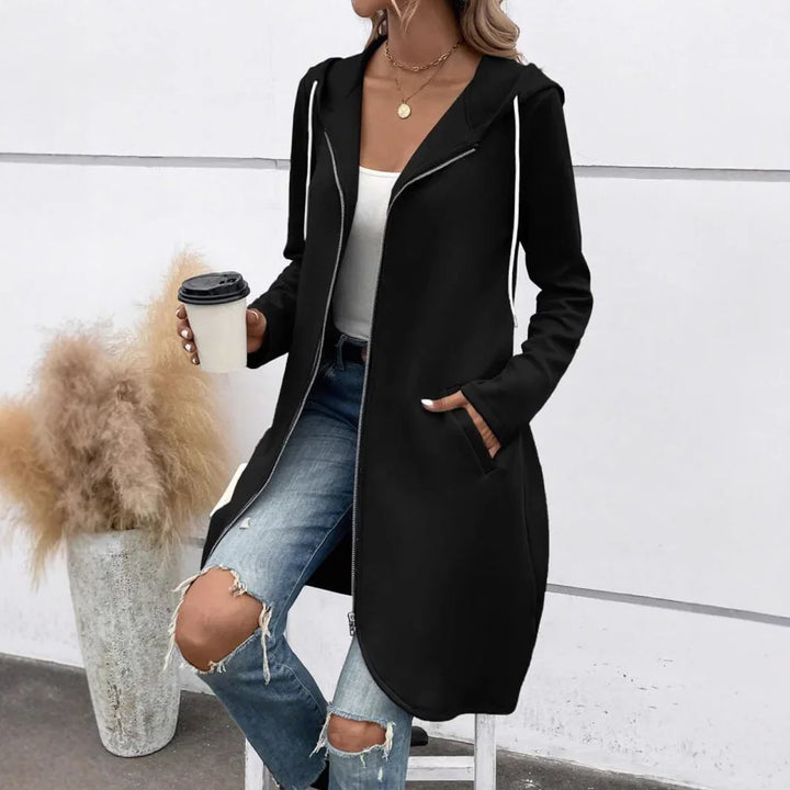 Woman wearing black long zip-up hoodie with white drawstrings and ripped jeans holding coffee cup