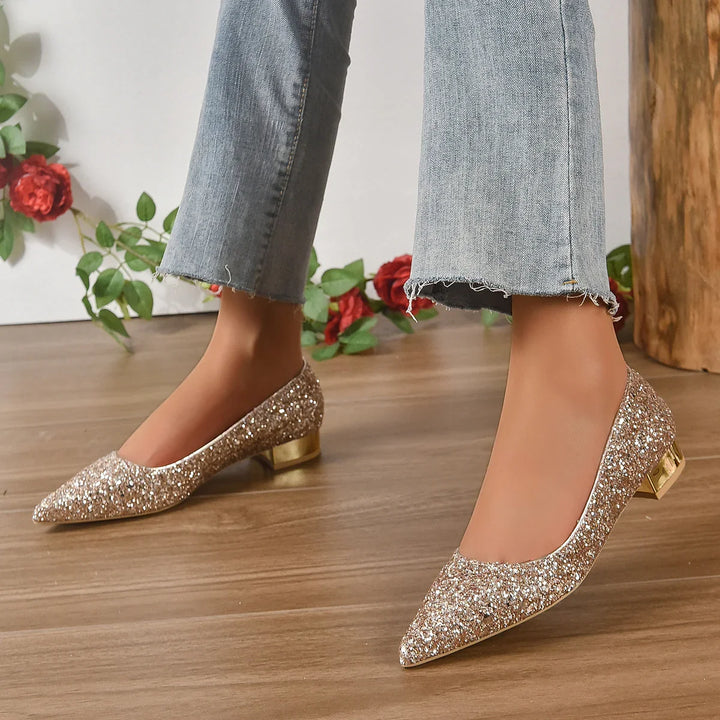 Woman wearing gold glitter pointed-toe low heel shoes with cropped frayed hem jeans on wooden floor