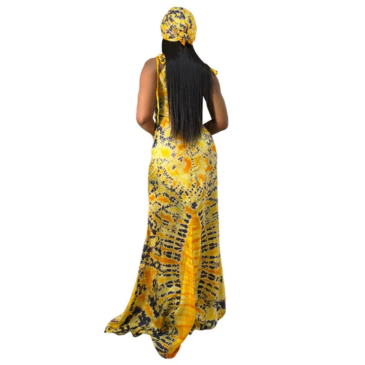 Woman wearing a yellow and black patterned maxi dress and matching headwrap, shown from the back