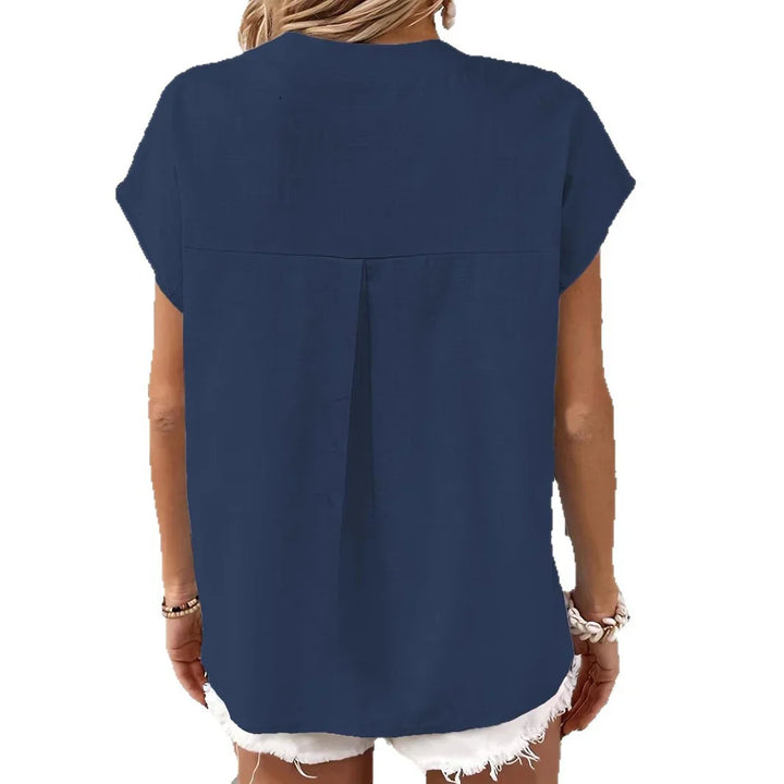 Back view of woman wearing navy blue short sleeve blouse and white distressed shorts
