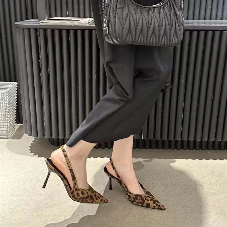Woman wearing leopard print slingback high heel shoes with black pants and a black quilted handbag