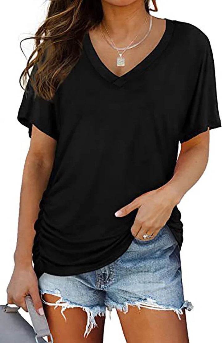 Woman wearing black V-neck short sleeve top and ripped denim shorts holding a gray bag