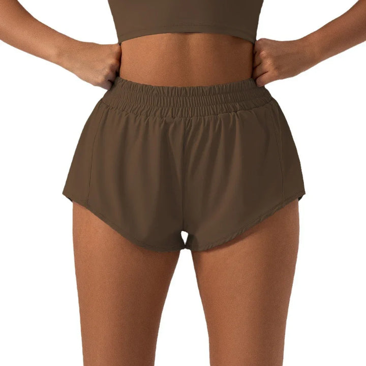 Woman wearing brown high-waisted athletic shorts with elastic waistband and side vents