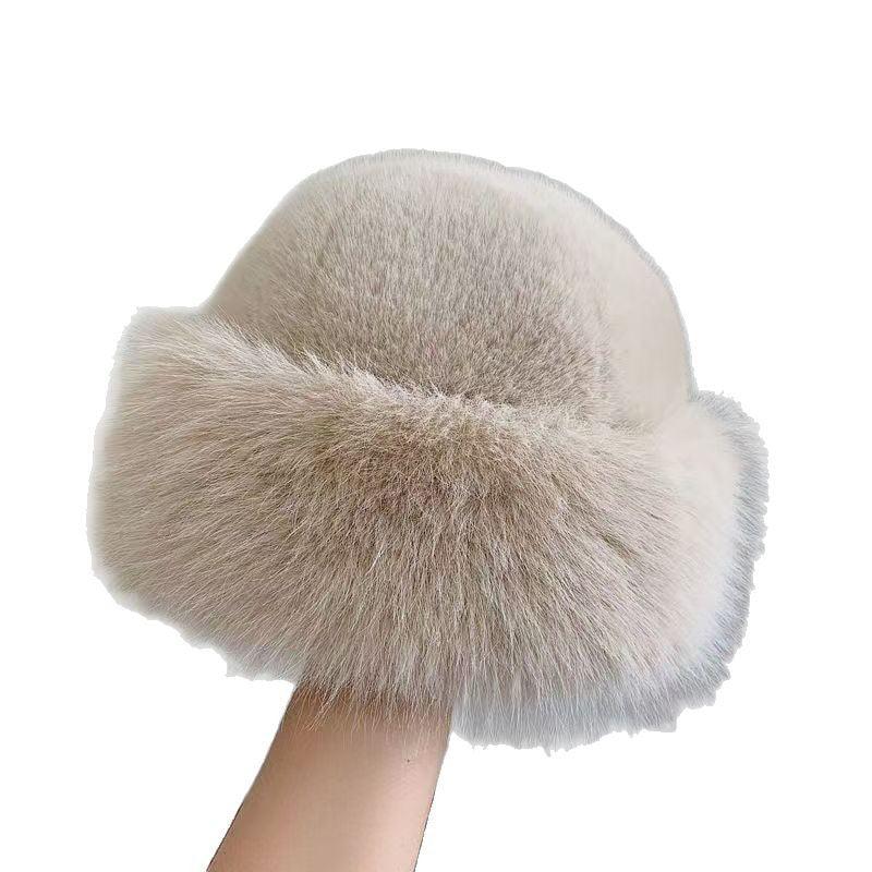 Soft beige faux fur winter hat with fluffy texture held in hand on white background