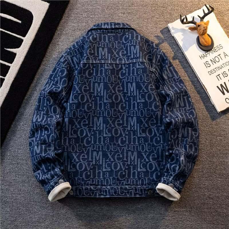 Blue denim jacket with repeating white text pattern laid flat on gray carpet next to decorative deer head and inspirational sign