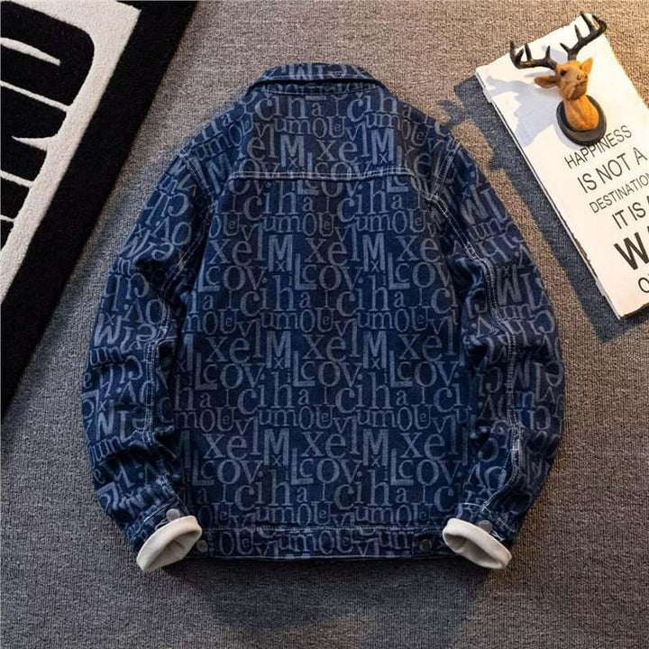 Blue denim jacket with repeating white text pattern laid flat on gray carpet next to decorative deer head and inspirational sign