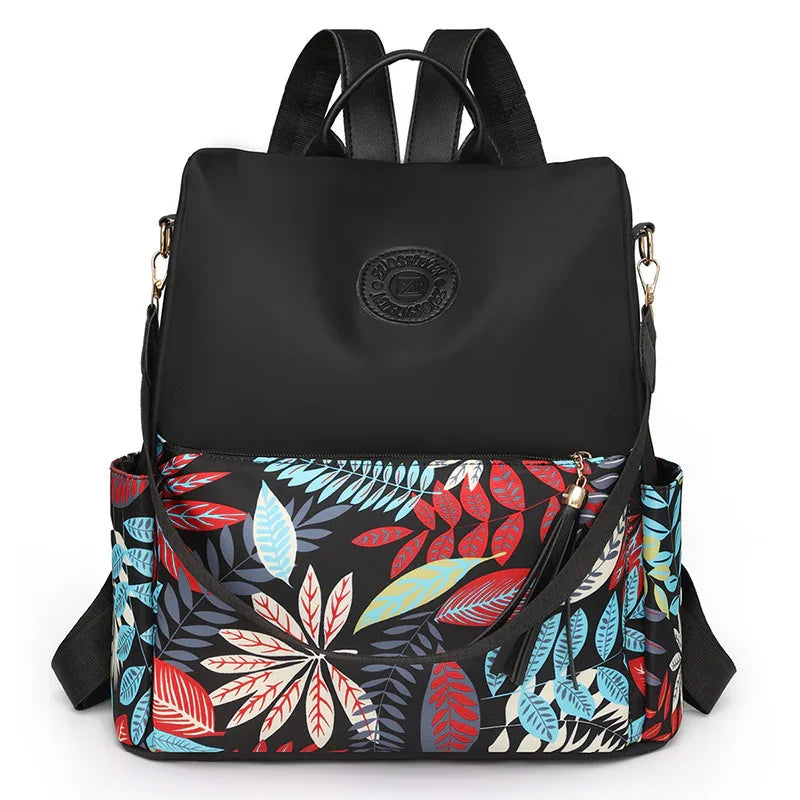 Black backpack with colorful red, blue, and white leaf pattern and front zipper pocket