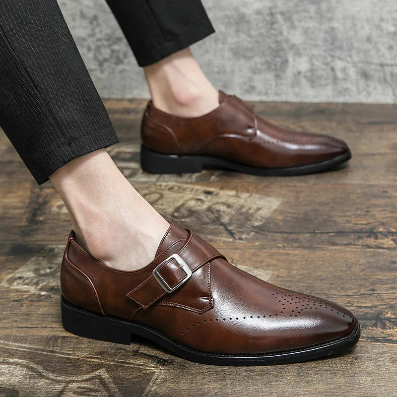 Men's brown leather monk strap dress shoes on wooden floor with black trousers