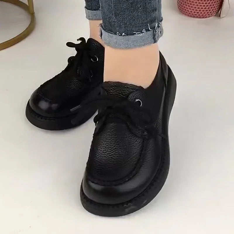 Black leather lace-up casual shoes worn with cuffed blue jeans on white floor