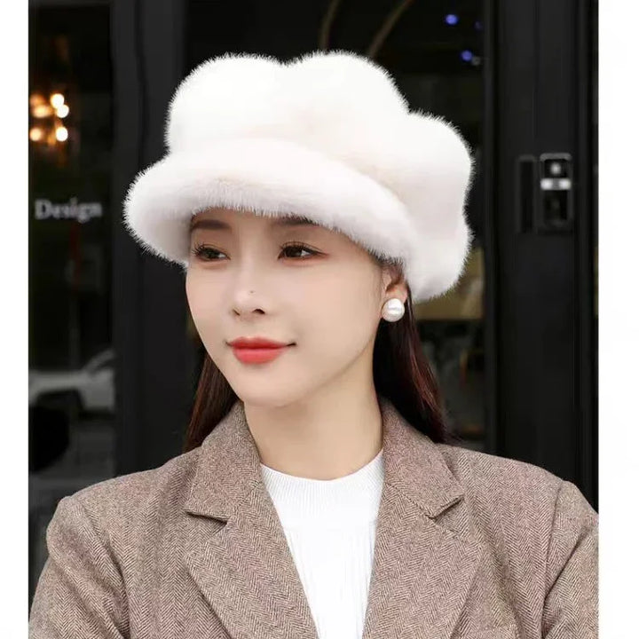 Woman wearing white fluffy hat, pearl earrings, beige blazer, and white top in outdoor setting