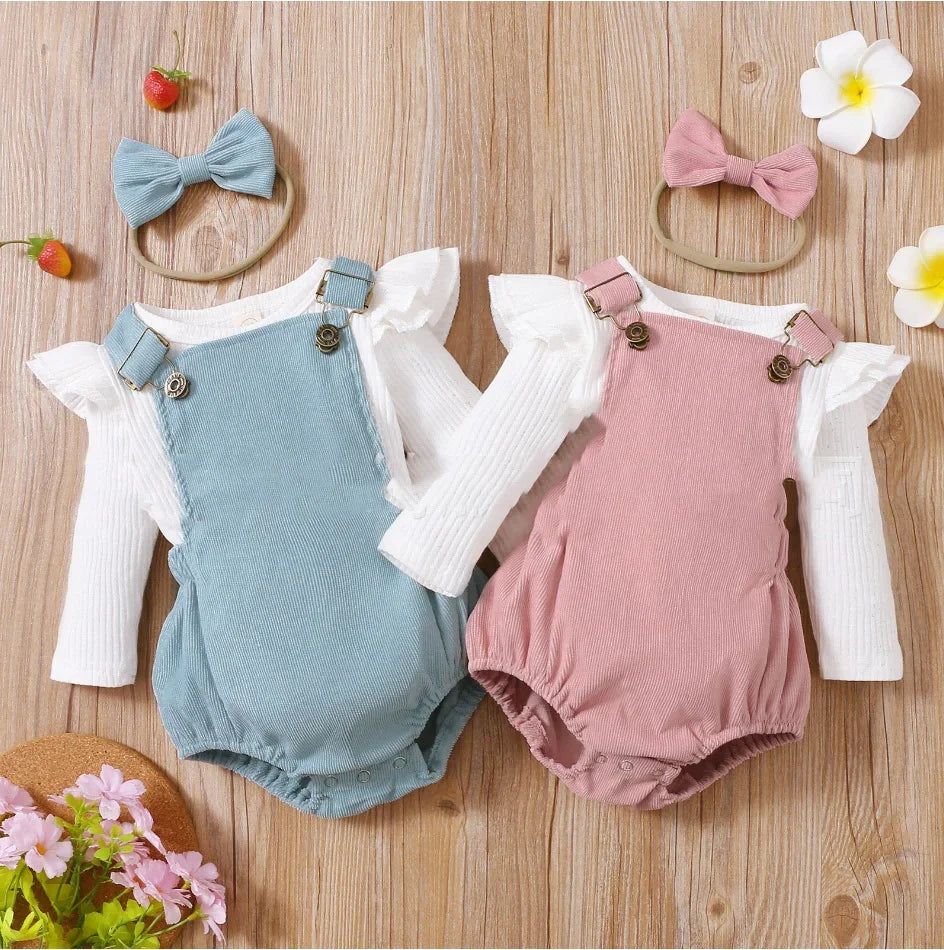 Two baby rompers in blue and pink with white long-sleeve tops and matching bow headbands on wood background