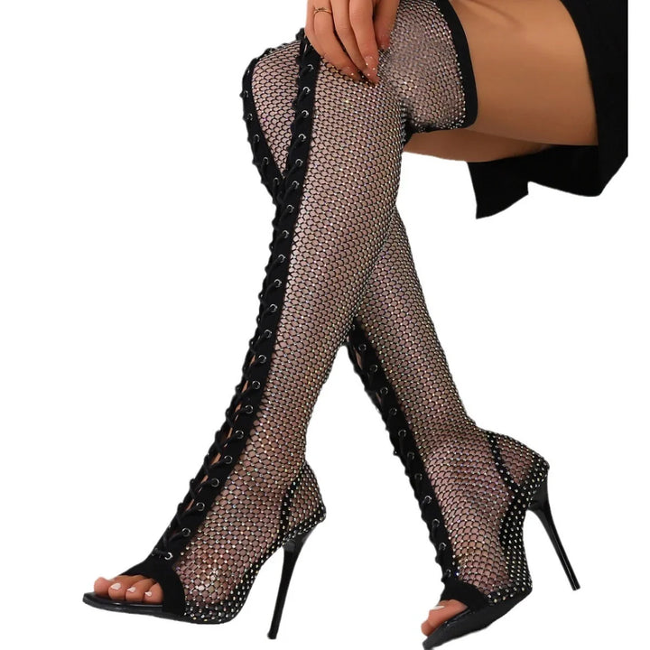 Black fishnet thigh-high boots with laces and high heels on model legs