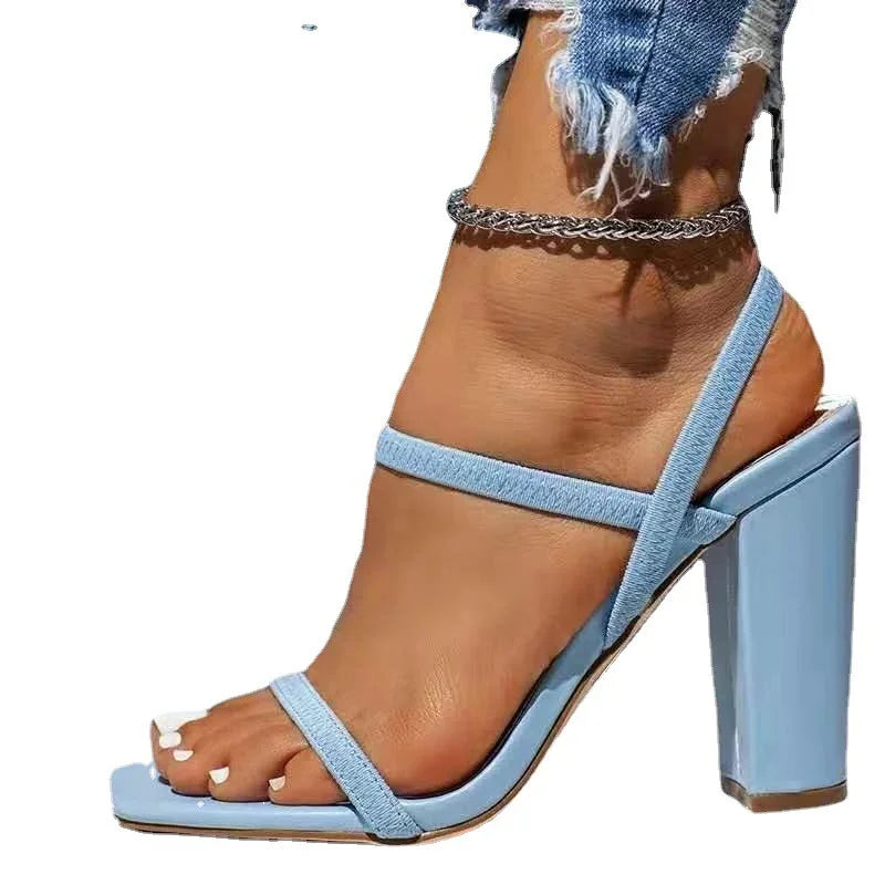 Woman wearing light blue block heel sandals with thin straps and ankle chain accessory