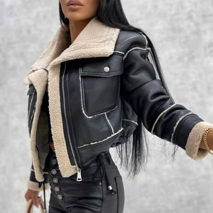Woman wearing black leather cropped jacket with beige sherpa lining and high-waisted black pants