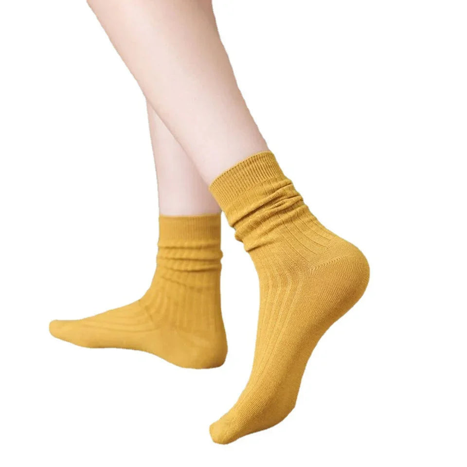 Person wearing mustard yellow ribbed ankle socks on white background