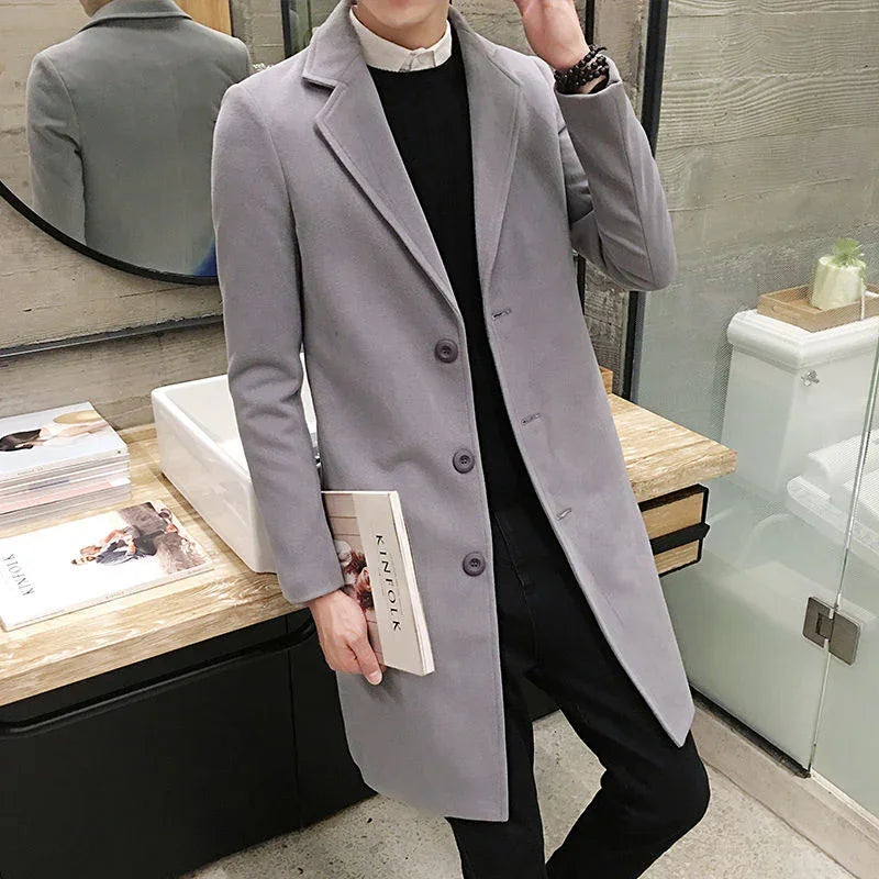 Man wearing stylish light gray wool coat holding Kinfolk magazine in modern bathroom setting