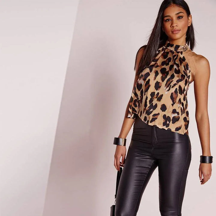 Woman wearing leopard print halter top and black leather pants posing against plain background