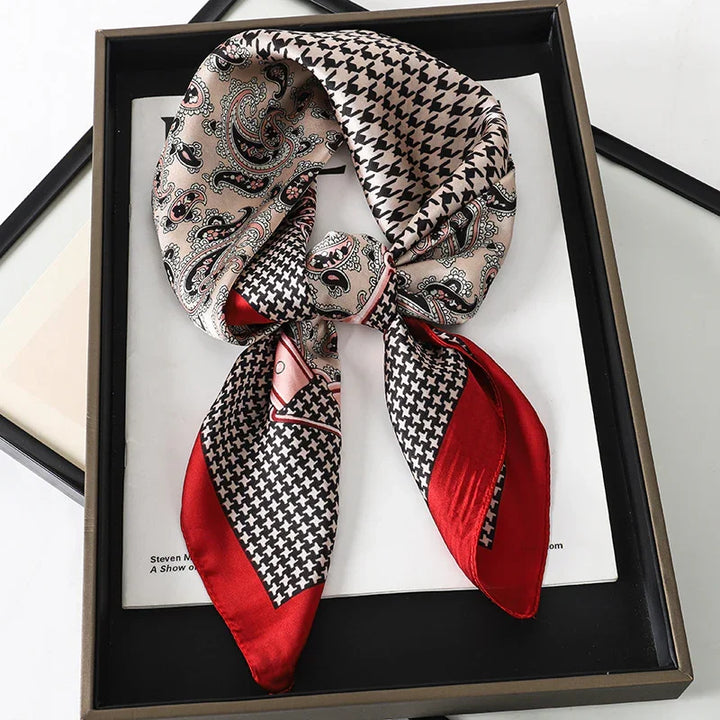 Silk scarf with paisley and houndstooth patterns in beige, black, and red, displayed in a black frame