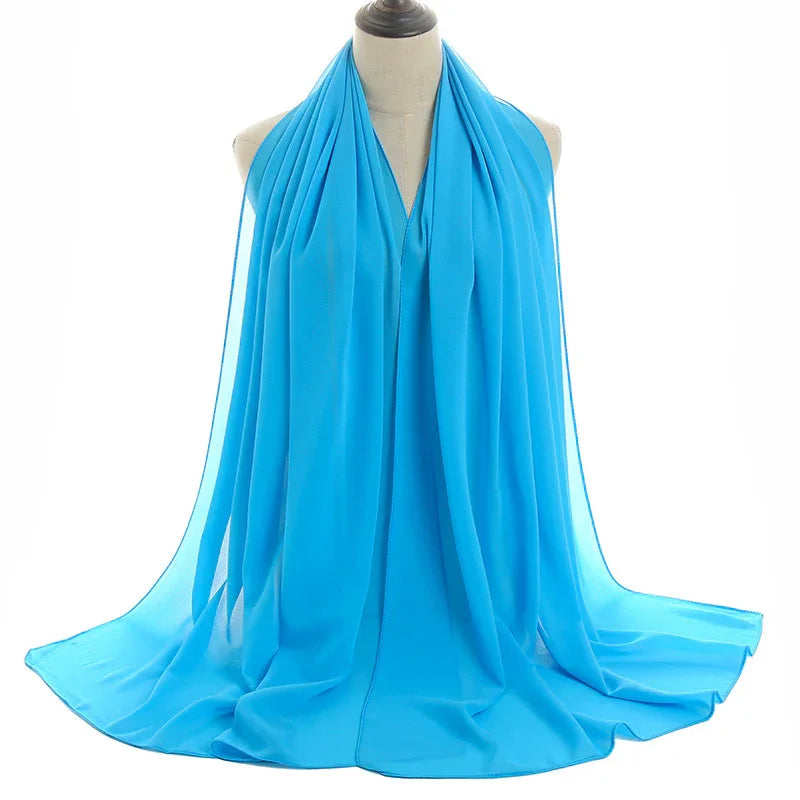 Bright blue chiffon scarf displayed on a dress form with soft pleats and flowing drape