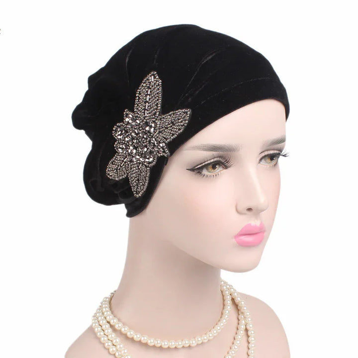 Elegant black velvet turban with jeweled floral brooch on mannequin wearing pearl necklace