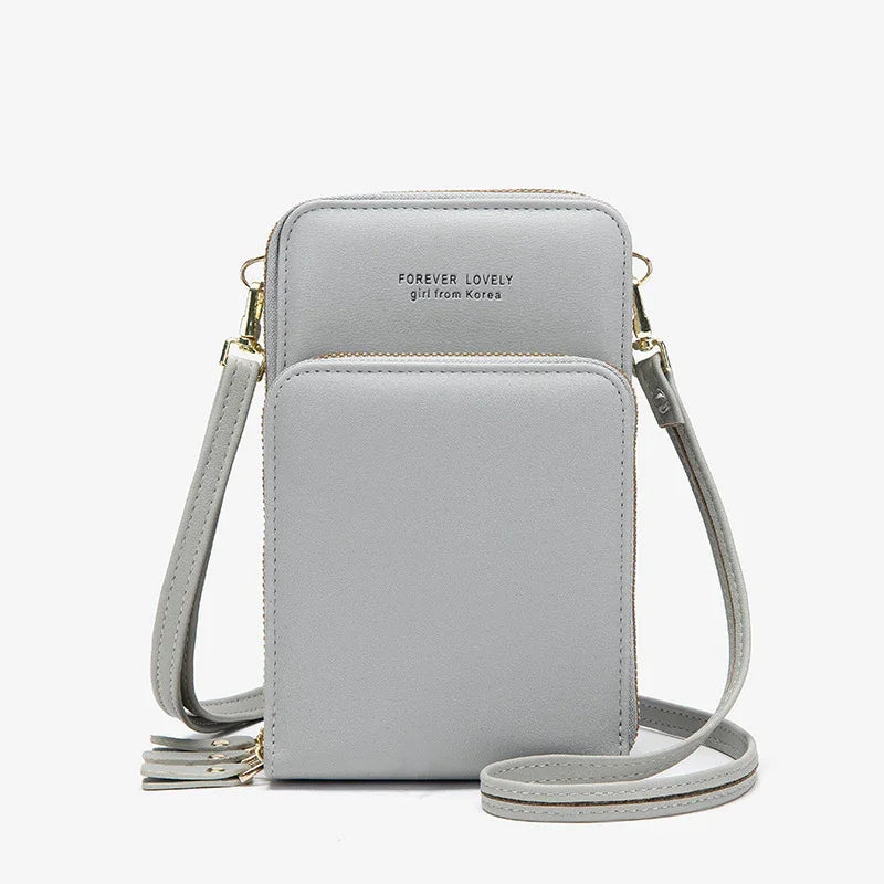 Light gray compact crossbody bag with gold zippers, front pocket, and detachable strap