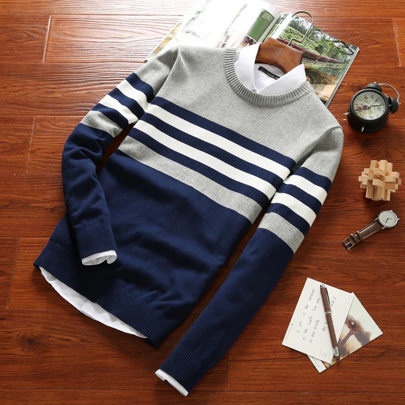 Men's striped blue and gray knit sweater with white shirt collar on wooden surface with watch, clock, and notes