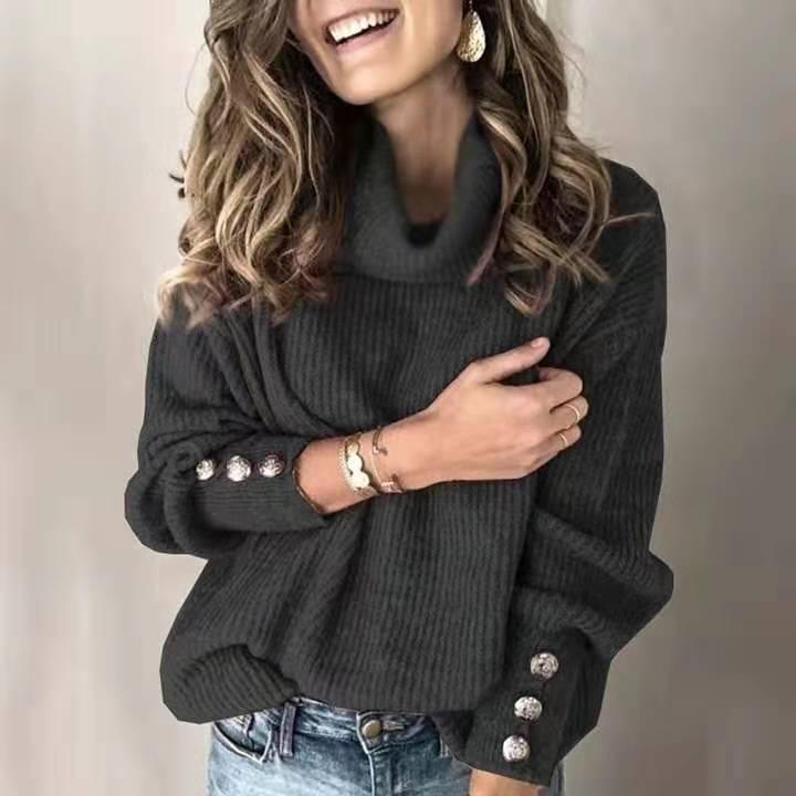 Woman wearing dark gray ribbed turtleneck sweater with decorative silver buttons and blue jeans