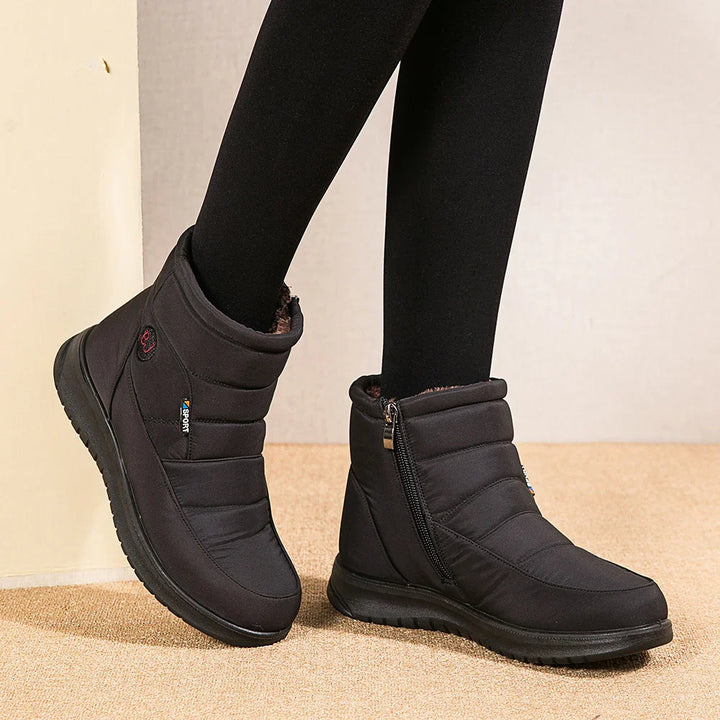 Black insulated winter boots with side zipper and sport tag worn with black leggings on carpet