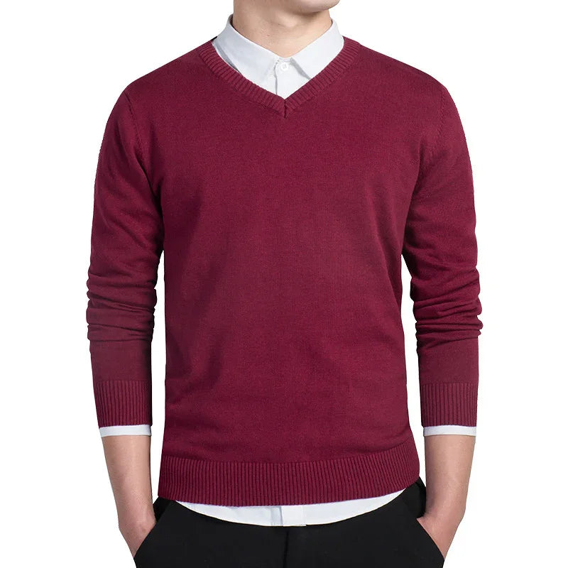 Man wearing burgundy V-neck sweater over white button-down shirt with black pants