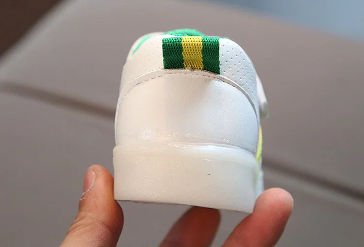 Close-up of white sneaker heel with green and yellow striped fabric detail, held by hand