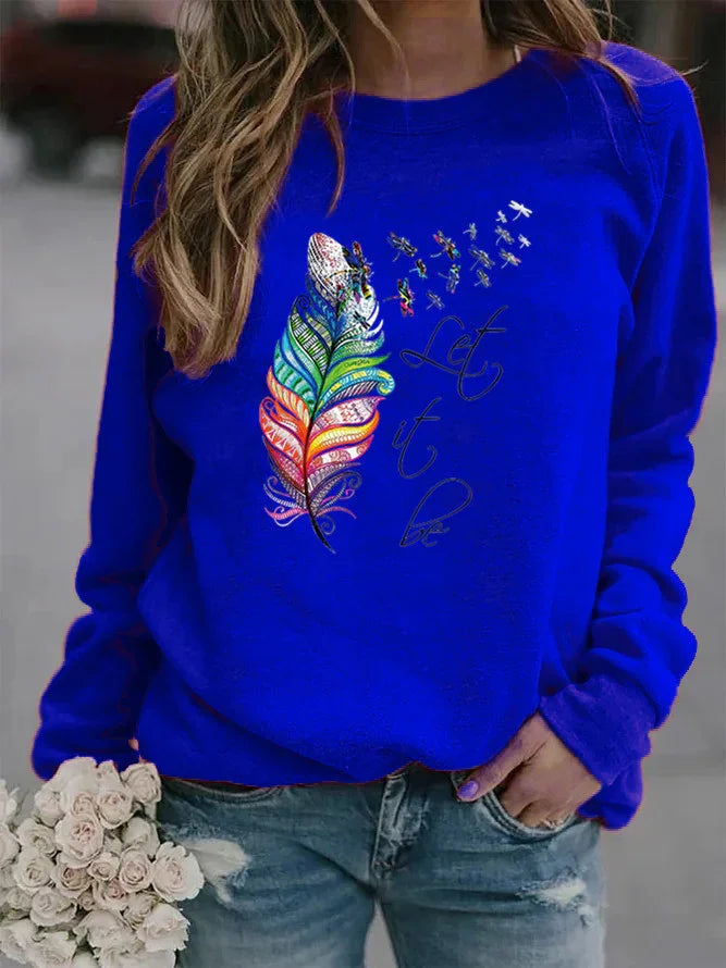 Woman wearing royal blue sweatshirt with colorful feather and dragonfly design, text 'Let it be', holding white roses