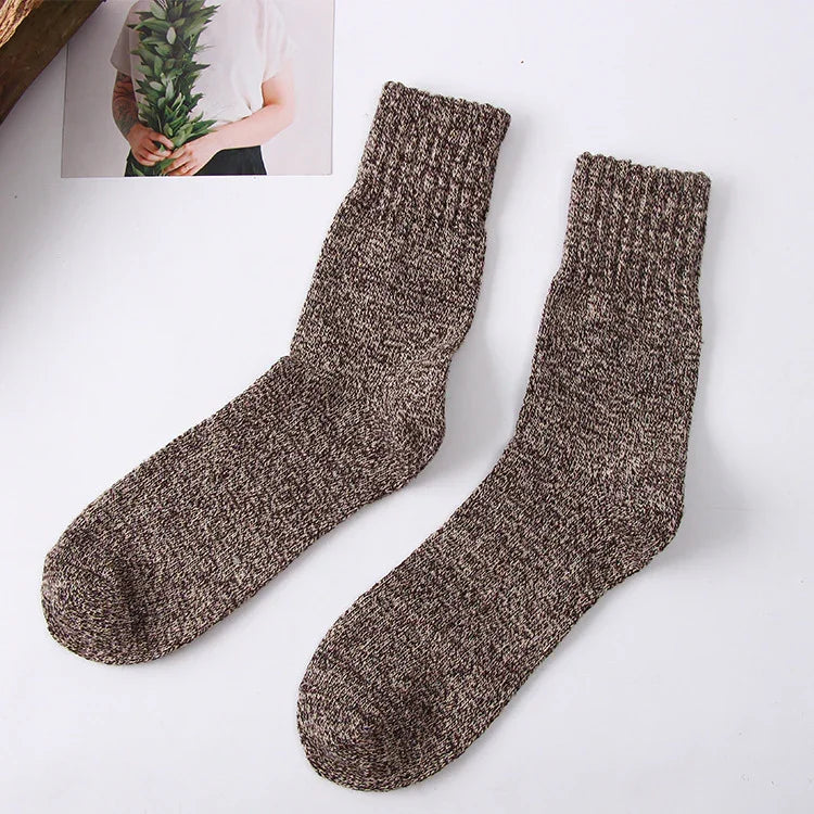 Pair of brown marled wool blend warm cozy socks on white background with photo of person holding green leaves