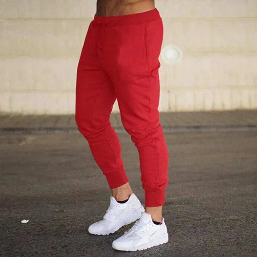 Close-up of person wearing bright red jogger pants and white sneakers on asphalt surface