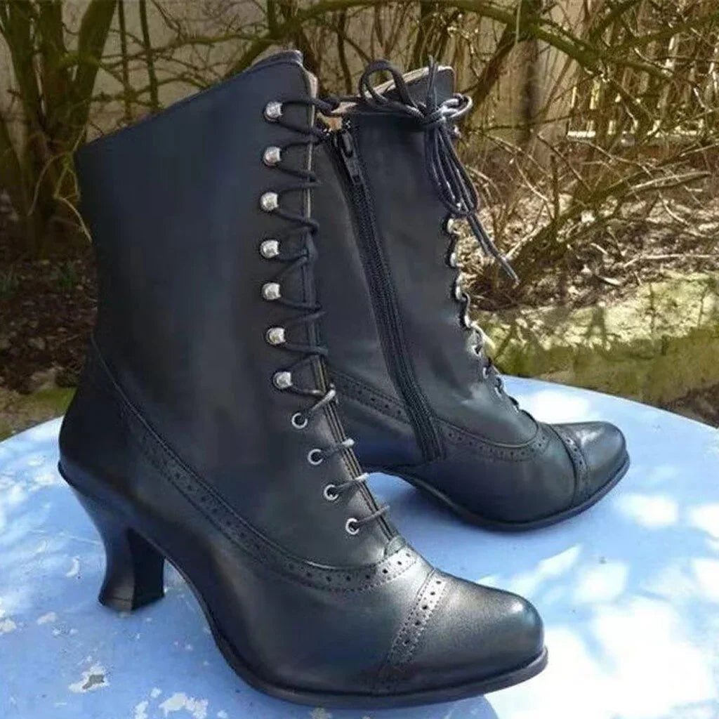 Black leather vintage lace-up heeled ankle boots with side zipper on blue surface outdoors